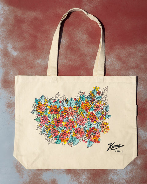 Beige tote bag with floral design and 'Karma Coffee' branding on a textured background