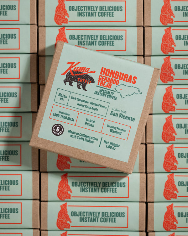 Kuma Honduras coffee packaging on a stack of Kuma Instant Coffee boxes.
